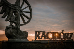 Das steinerne Wappen von Raciborz, Ratibor, am Ortseingang im Sonnenaufgang, unten eine Spiegelung des Wappens in einer Pfütze Das steinerne Wappen von Raciborz, Ratibor, am Ortseingang im Sonnenaufgang, unten eine Spiegelung des Wappens in einer Pfütze